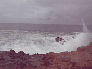moving image of a wave crashing into a rock creating a giant spray